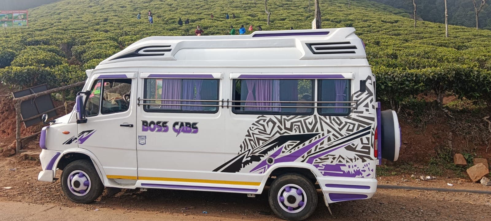White Tempo Traveller parked beside a hillside tea plantation
