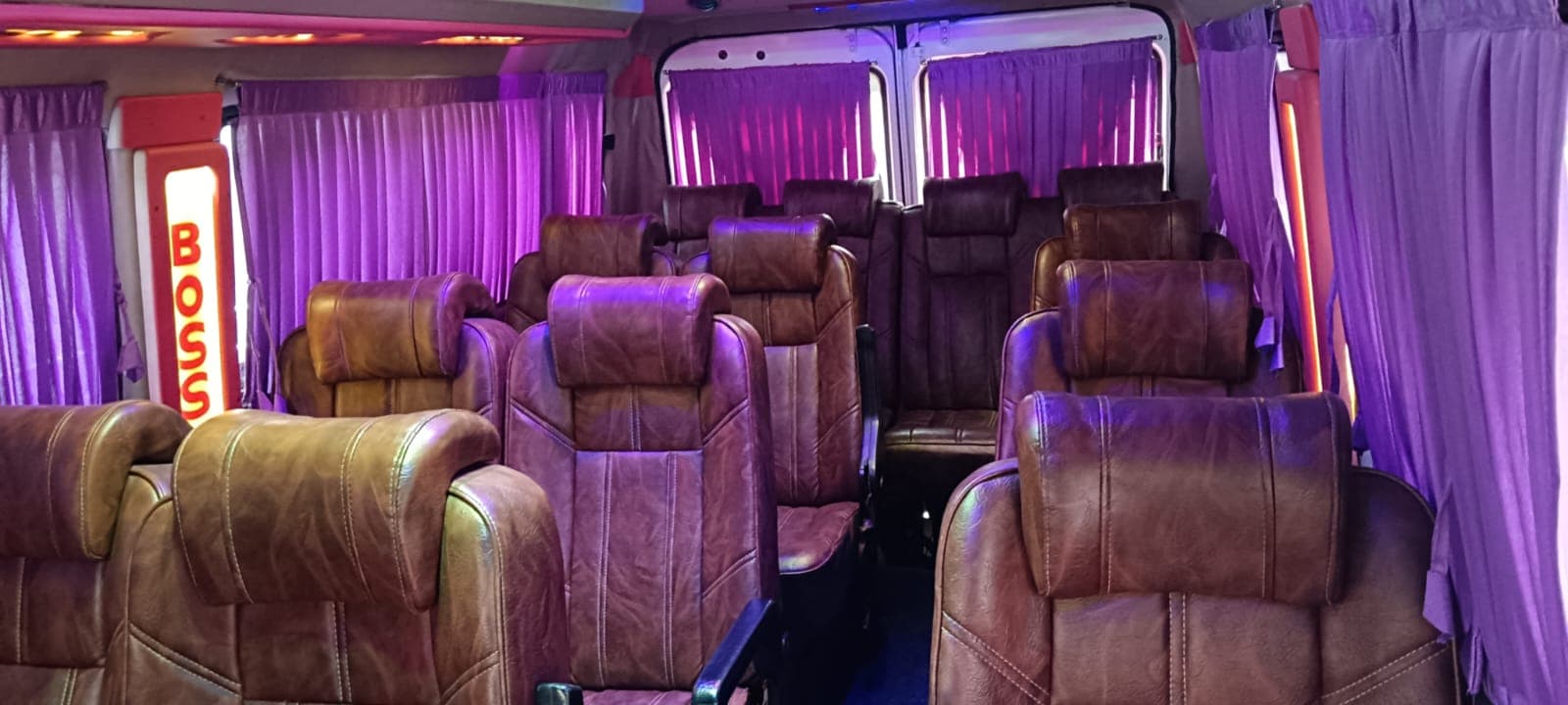 Tempo Traveller interior with brown leather seats and purple curtains