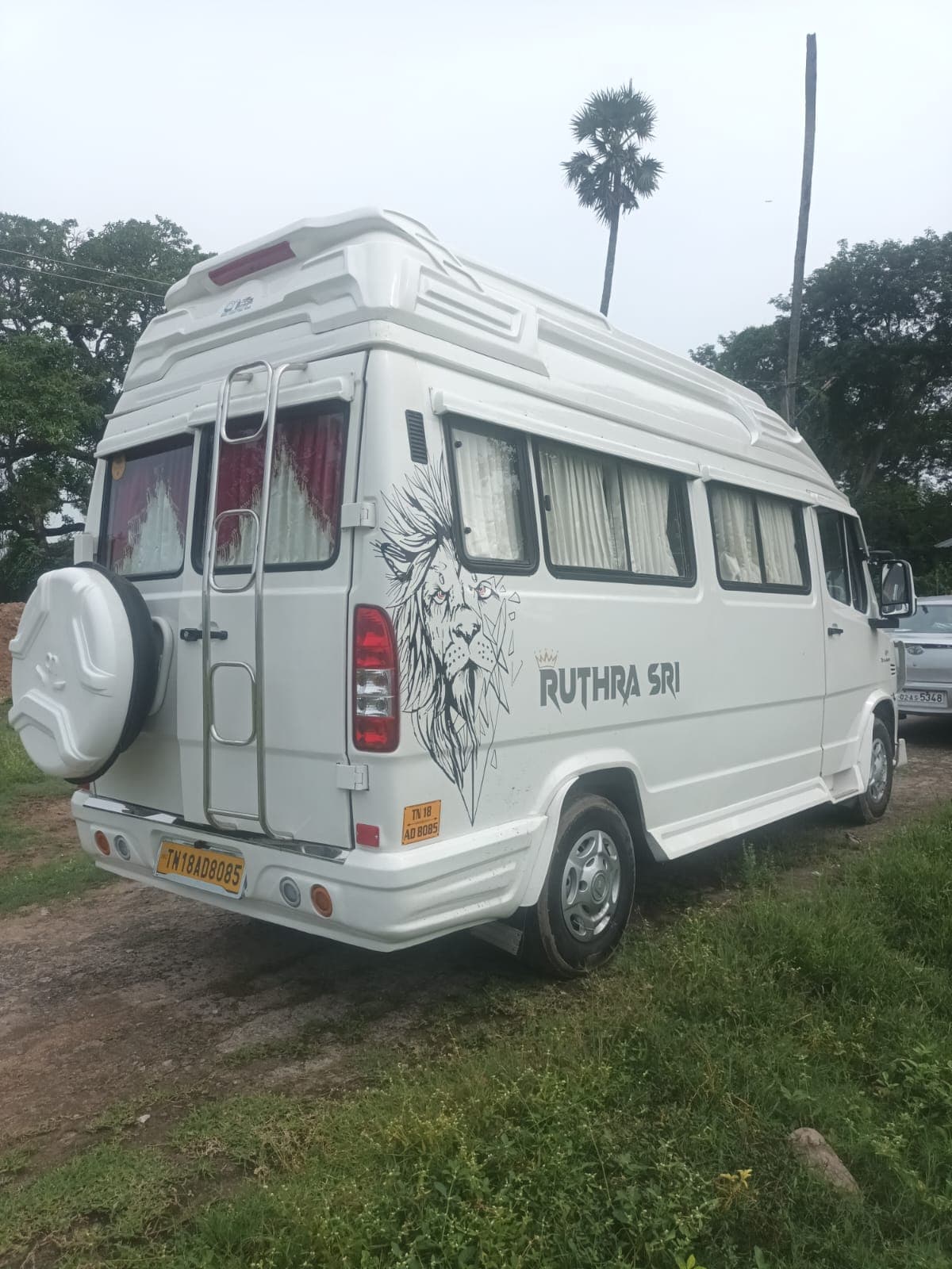 White Tempo Traveller rear three-quarter view with a lion decal and rear spare wheel