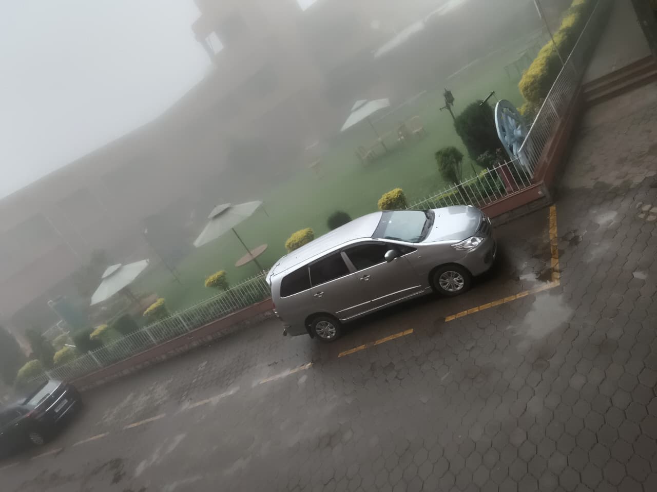 Silver Toyota Innova parked at a misty hill-station resort