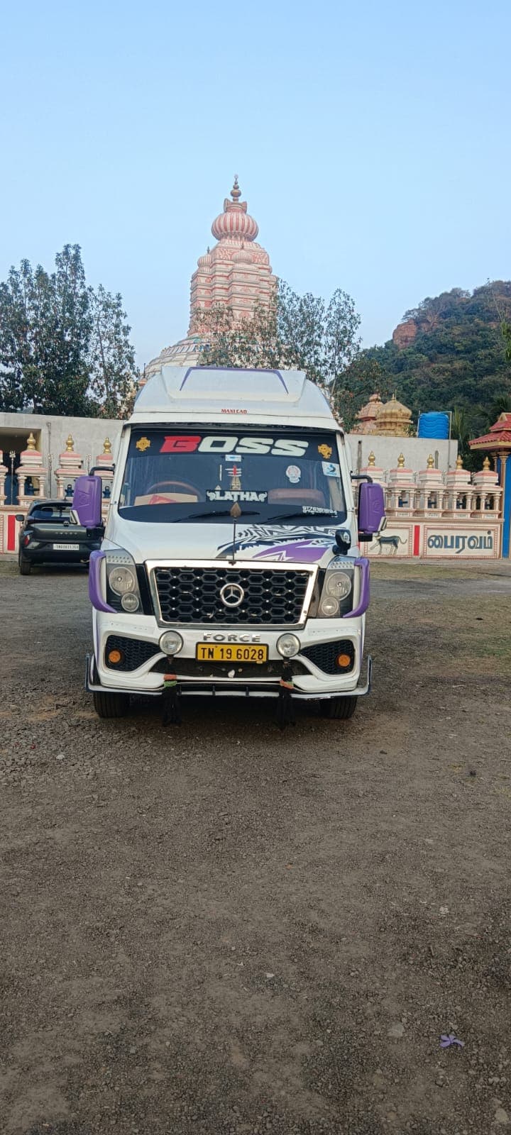 White Tempo Traveller parked in front of a temple gopuram at dawn